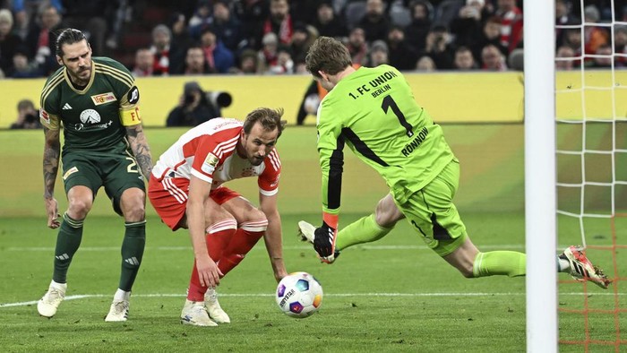 Bayerns Harry Kane, center, and Unions goalkeeper Frederik Ronnow battle for the ball during the German Bundesliga soccer match between Bayern Munich and Union Berlin at the Allianz Arena in Munich, Germany, Wednesday, Jan. 24, 2024. (Sven Hoppe/dpa via AP)