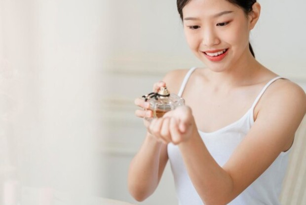 Perempuan sedang menyemprotkan parfum