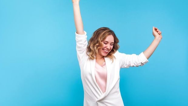 portrait of a businesswoman smiling happily with a fist in the air because she has won an award by looking at her mobile phone.