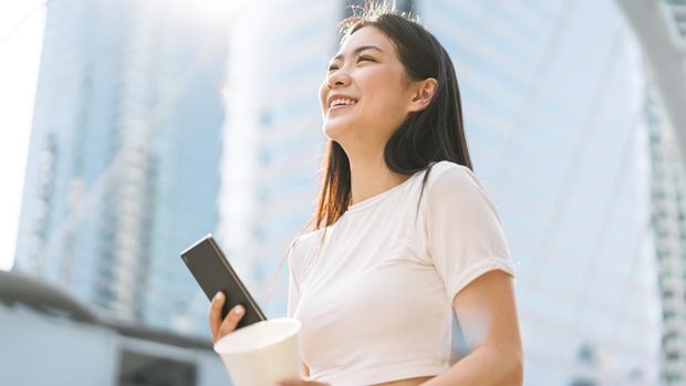 portrait of a businesswoman smiling happily with a fist in the air because she has won an award by looking at her mobile phone.