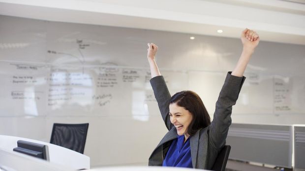 portrait of a businesswoman smiling happily with a fist in the air because she has won an award by looking at her mobile phone.