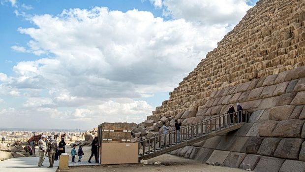 Visitors pose for a picture by the base of the Pyramid of Menkaure (or Menkheres, built in the 26th century BC) at the Giza Pyramids Necropolis, west of Cairo, on January 29, 2024. In a video posted on Facebook on January 26, Mostafa Waziri, the head of Egypt's Supreme Council of Antiquities, showed workers setting blocks of granite on the base of the pyramid, dubbing it 