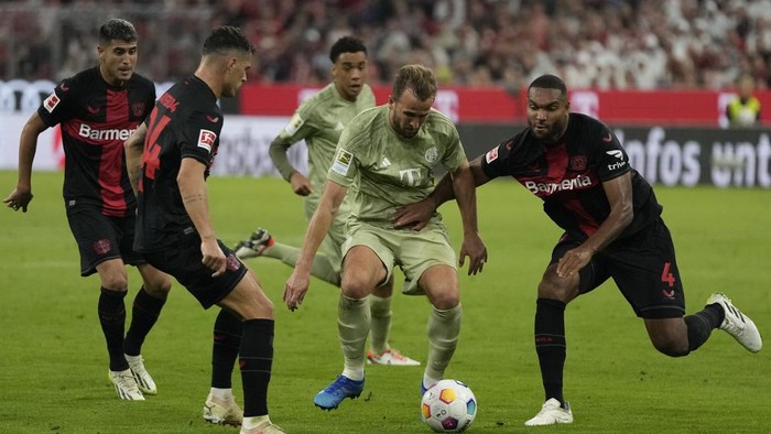 Bayerns Harry Kane, centre, is challenged by Leverkusens Jonathan Tah during the German Bundesliga soccer match between Bayern Munich and Bayer 04 Leverkusen, at the Allianz Arena stadium in Munich, Germany, Friday, Sept. 15, 2023. (AP Photo/Matthias Schrader)