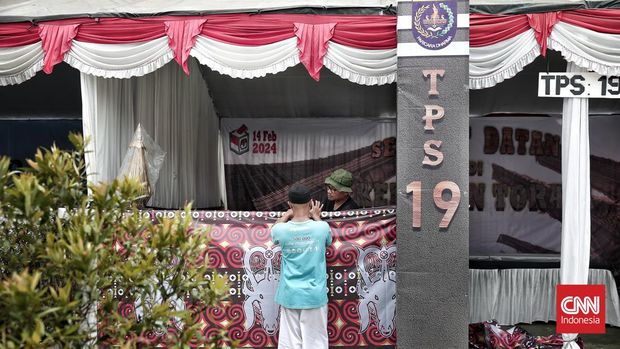 Warga menyiapkan dekorasi untuk persiapan tempat pemungutan suara (TPS) di Jalan Nenas Raya, Pancoran Mas, Depok, Jawa Barat, Selasa (13/2/2024). (CNN Indonesia/Andry Novelino)