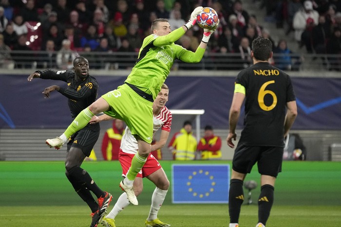 Real Madrids goalkeeper Andriy Lunin saves a ball in front of Leipzigs Dani Olmo during the Champions League round of 16 first leg soccer match between RB Leipzig and Real Madrid at the Red Bull arena stadium in Leipzig, Germany, Tuesday, Feb. 13, 2024. (AP Photo/Matthias Schrader)