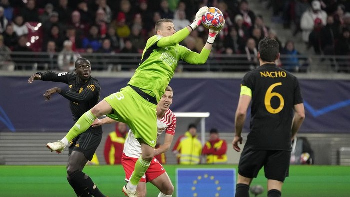 Real Madrids goalkeeper Andriy Lunin saves a ball in front of Leipzigs Dani Olmo during the Champions League round of 16 first leg soccer match between RB Leipzig and Real Madrid at the Red Bull arena stadium in Leipzig, Germany, Tuesday, Feb. 13, 2024. (AP Photo/Matthias Schrader)