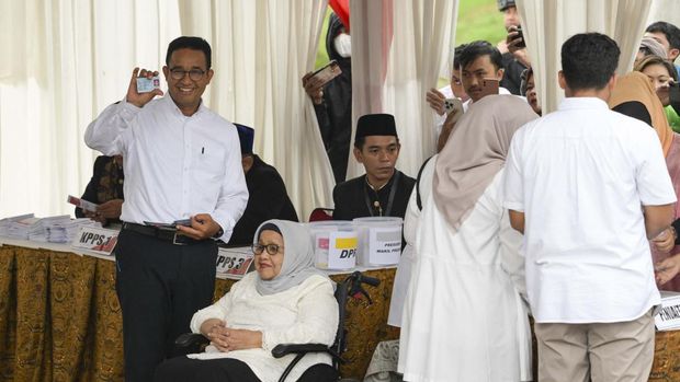 Presidential candidate Anies Baswedan (L) shows his ID as he arrives to cast his ballot to vote in Indonesia's presidential and legislative elections at a polling station in Jakarta on February 14, 2024. Voting began on February 14 in Indonesia's presidential, national and provincial elections at more than 800,000 polling stations across the country, with nearly 205 million people eligible to cast their ballot. (Photo by BAY ISMOYO / AFP)