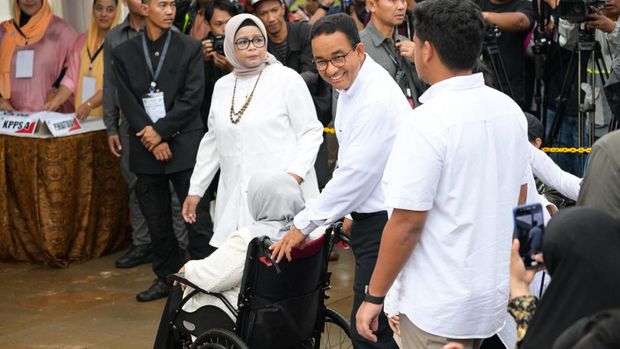Presidential candidate Anies Baswedan (C) pushes his mother in a wheelchair as they arrive to cast their ballots to vote in Indonesia's presidential and legislative elections at a polling station in Jakarta on February 14, 2024. Voting began on February 14 in Indonesia's presidential, national and provincial elections at more than 800,000 polling stations across the country, with nearly 205 million people eligible to cast their ballot. (Photo by BAY ISMOYO / AFP)