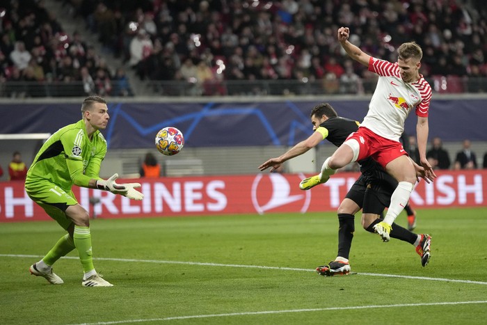Leipzigs Dani Olmo, right, misses the ball in front of Real Madrids goalkeeper Andriy Lunin during the Champions League round of 16 first leg soccer match between RB Leipzig and Real Madrid at the Red Bull arena stadium in Leipzig, Germany, Tuesday, Feb. 13, 2024. (AP Photo/Matthias Schrader)