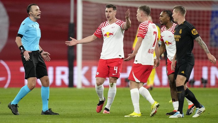 Leipzigs Willi Orban and Leipzigs Dani Olmo complain to referee Irfan Peljto, left, during the Champions League round of 16 first leg soccer match between RB Leipzig and Real Madrid at the Red Bull arena stadium in Leipzig, Germany, Tuesday, Feb. 13, 2024. (AP Photo/Matthias Schrader)