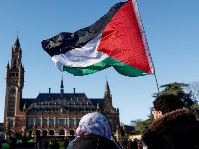 Bendera Palestina dibawa demonstran yang berkumpul di luar gedung Mahkamah Internasional Protesters hold a Palestinian flag as they gather outside the International Court of Justice (ICJ) as judges rule on emergency measures against Israel following accusations by South Africa that the Israeli military operation in Gaza is a state-led genocide, in The Hague, Netherlands, January 26, 2024. REUTERS/Piroschka van de Wouw/File Photo Purchase Licensing Rights