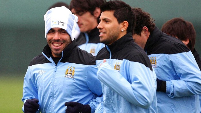 Manchester Citys Carlos Tevez, left, smiles as he runs alongside Sergio Aguero during a training session at Carrington, Manchester, England, Wednesday, March 14, 2012. Manchester City face Sporting Lisbon in their Europa League match tomorrow. (AP Photo/Dave Thompson/PA) UNITED KINGDOM OUT: NO SALES: NO ARCHIVE