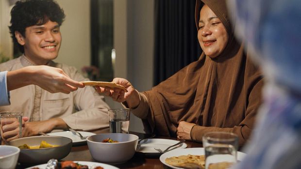 Eid Mubarak Muslim Asia family have Iftar dinner sister share bread to sibling for break fasting. Traditional food during Ramadan month at home, The Islamic Halal Eat and Drink at modern Islam.