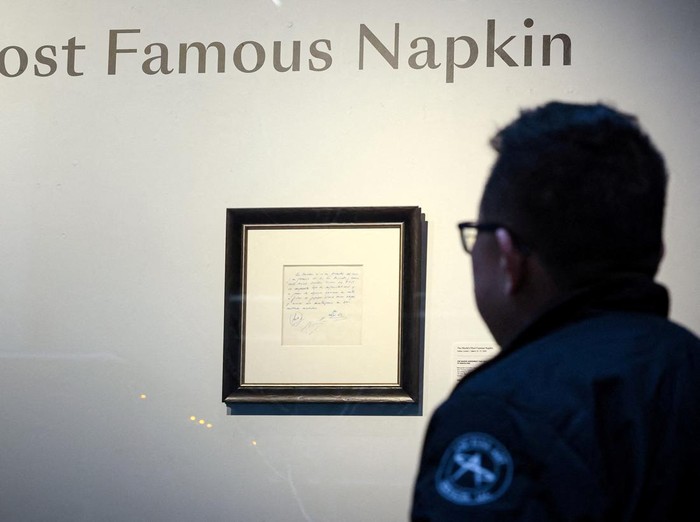 A guest looks at a napkin, written on by Barcelona's Sporting Director at that time Carles Rexach on December 14, 2000, promising a contract to secure 13-year-old Lionel Messi for FC Barcelona, on display at Bonhams Auctions in New York City, U.S., March 6, 2024.  REUTERS/Brendan McDermid
