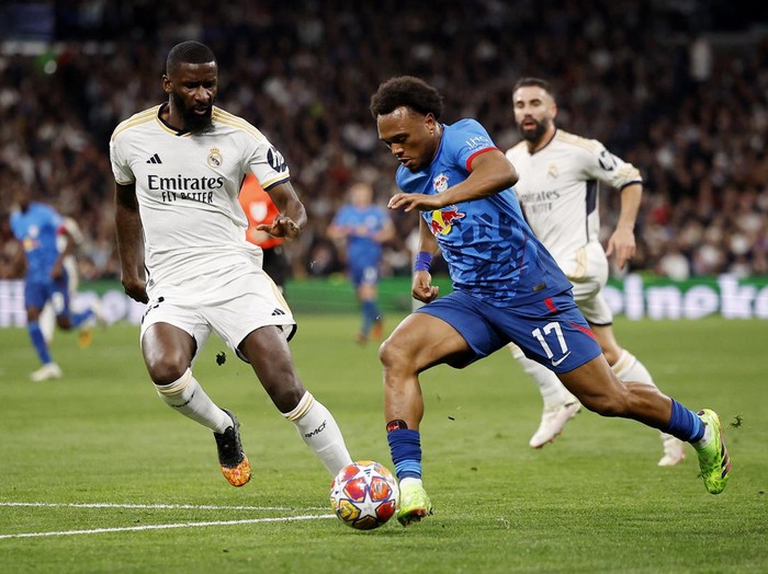 Susah Payah Real Madrid Lolos ke Perempatfinal Liga Champions Soccer Football - Champions League - Round of 16 - Second Leg - Real Madrid v RB Leipzig - Santiago Bernabeu, Madrid, Spain - March 6, 2024 RB Leipzig's Lois Openda in action with Real Madrid's Antonio Rudiger REUTERS/Juan Medina