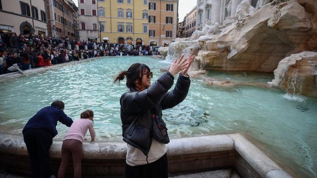 Yuting, from China, throws two coins into the Trevi Fountain in Rome, Italy, February 16, 2024. As visitors' coins splash into Rome's majestic Trevi Fountain carrying wishes for love, good health or a return to the Eternal City, they provide practical help to people the tourists will never meet. For hundreds of years, when in Rome, visitors have flocked to the fountain to make a wish, following a storied ritual. Few gave their coins a second thought. Today, coins pile up for several days before they are fished out and taken to the Rome division of the worldwide Catholic charity Caritas, which counts the bucketfuls of change and uses them to fund a food bank, soup kitchen and welfare projects. 