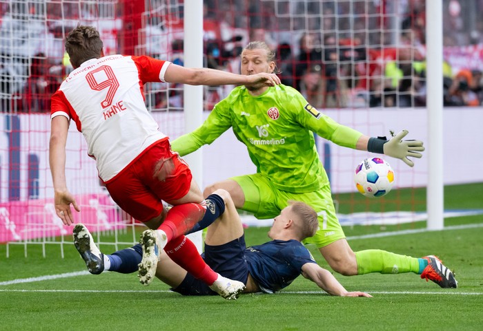 09 March 2024, Bavaria, Munich: Soccer: Bundesliga, Bayern Munich - FSV Mainz 05, matchday 25 at the Allianz Arena. Harry Kane (l) of Munich and Andreas Hanche Olsen (bottom) and Robin Zentner of Mainz fight for the ball. Photo: Sven Hoppe/dpa - IMPORTANT NOTE: In accordance with the regulations of the DFL German Football League and the DFB German Football Association, it is prohibited to utilize or have utilized photographs taken in the stadium and/or of the match in the form of sequential images and/or video-like photo series. (Photo by Sven Hoppe/picture alliance via Getty Images)