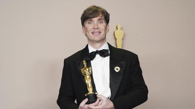 Christopher Nolan poses in the press room with the awards for best director and best picture for 