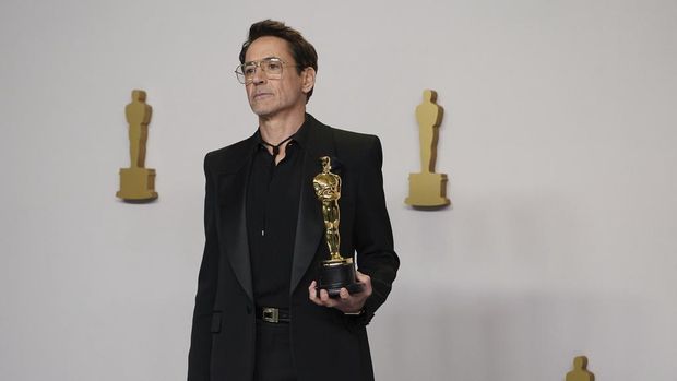Robert Downey Jr. poses in the press room with the award for best performance by an actor in a supporting role for 