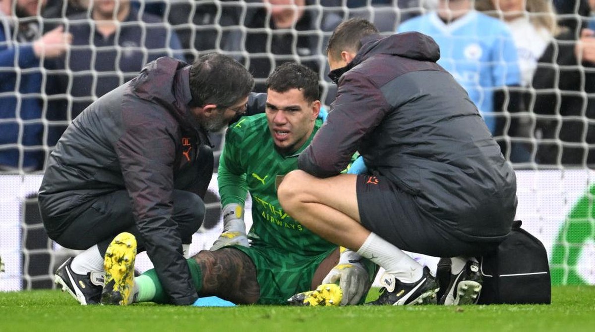 Ederson (tengah) saat mendapat perawatan medis di tengah laga melawan Liverpool. Foto: Getty Images/Michael Regan