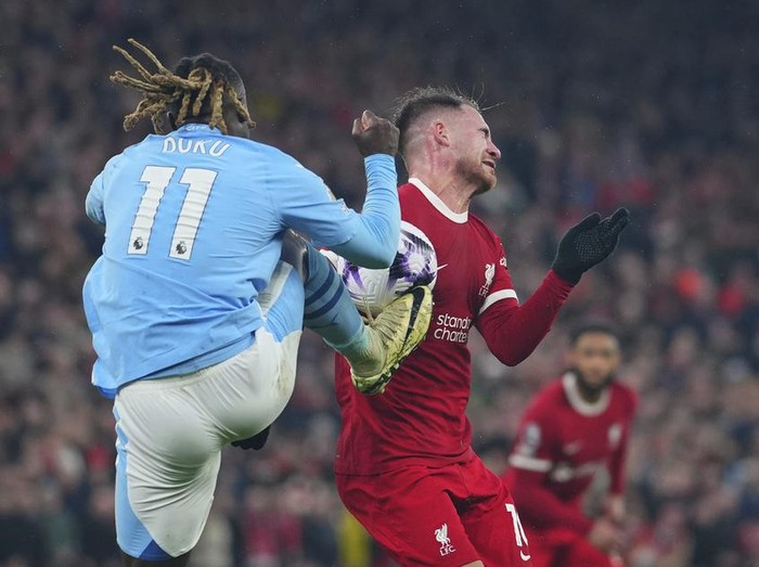 CAPTION CORRECTS PLAYER ID ON THE RIGHT Manchester City's Jeremy Doku, foreground, and Liverpool's Alexis Mac Allister fight for the ball during the English Premier League soccer match between Liverpool and Manchester City, at Anfield stadium in Liverpool, England, Sunday, March 10, 2024. (AP Photo/Jon Super)