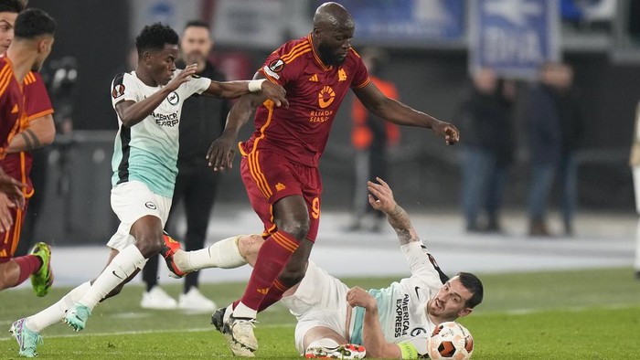Romas Romelu Lukaku, center, is challenged by Brightons Simon Adingra, left, during the Europa League round of sixteen first leg soccer match between Roma and Brighton and Hove Albion, at Romes Olympic Stadium, Thursday, March 7, 2024. (AP Photo/Alessandra Tarantino)