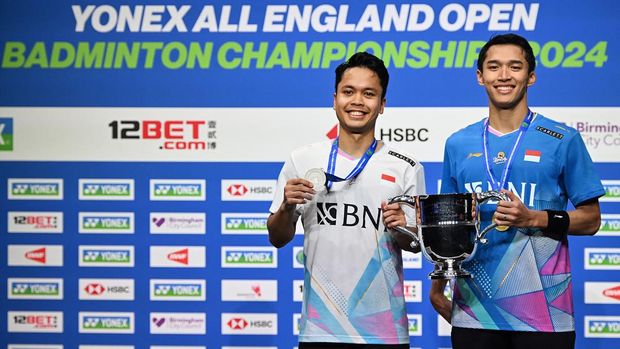 Jonatan Christie Juara All England 2024 Silver medallist Indonesia's Anthony Sinisuka Ginting (L) and gold medallist Indonesia's Jonatan Christie (R) celebrate on the podium after competing in the Men's Singles Final at the All England Open Badminton Championships at the Utilita Arena in Birmingham, central England, on March 17, 2024. (Photo by JUSTIN TALLIS / AFP)