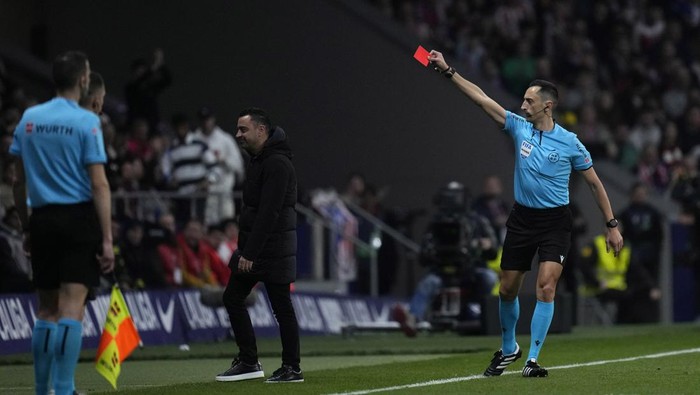 Referee Jose Maria Sanchez Martinez, right, shows a red card to Barcelonas head coach Xavi Hernandez, center, during the La Liga soccer match between Atletico Madrid and Barcelona at the Metropolitano stadium in Madrid, Spain, Sunday, March 17, 2024. (AP Photo/Bernat Armangue)