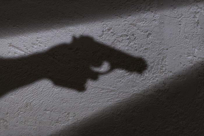 A shadow of a hand holding a gun in his hand.