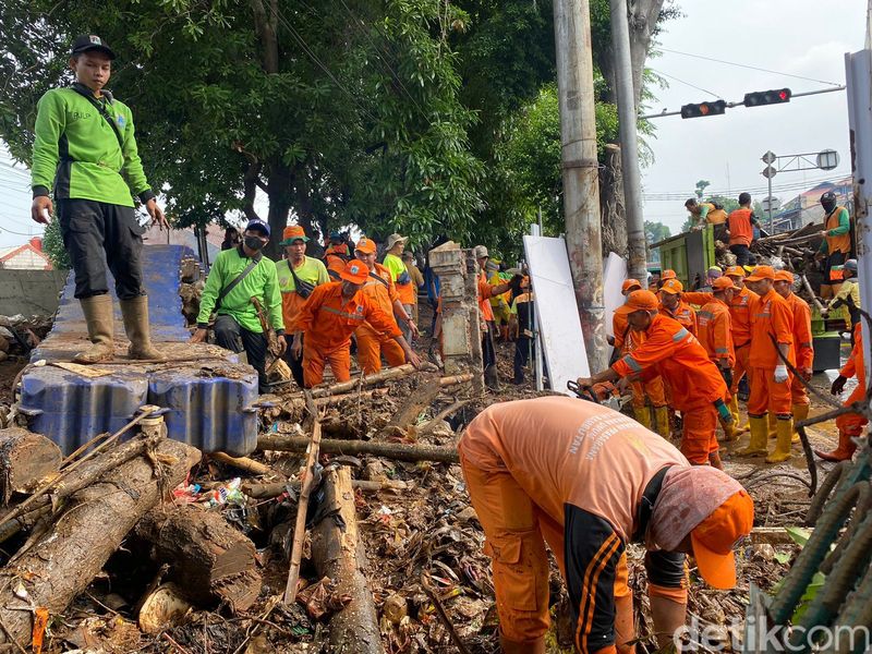 Petugas gabungan sedang menangani turap yang menjadi titik limpasan air yang menyebabkan banjir di pertigaan Hek Kramat Jati Jaktim (Devi P/detikcom)