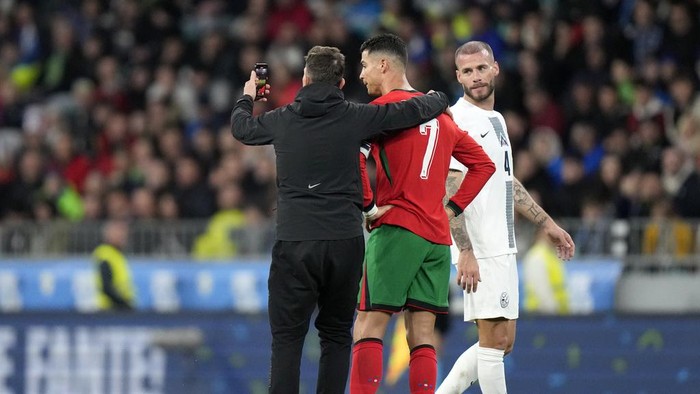 A pitch invader takes a selfie with Portugal's Cristiano Ronaldo during the international friendly soccer match between Slovenia and Portugal at the Stozice stadium in Ljubljana, Slovenia, Tuesday, March 26, 2024. (AP Photo/Darko Bandic)