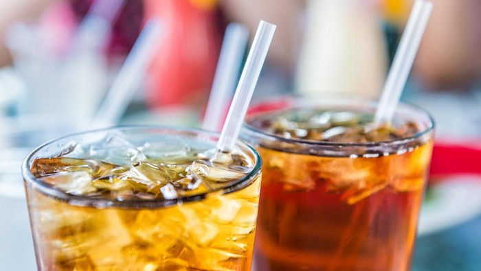Macro closeup of iced tea or soda with ice cubes and straw in glass