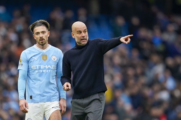 Manchester Citys head coach Pep Guardiola, right, speaks with Manchester Citys Jack Grealish at the end of the English Premier League soccer match between Manchester City and Arsenal at the Etihad stadium in Manchester, England, Sunday, March 31, 2024. (AP Photo/Dave Thompson)