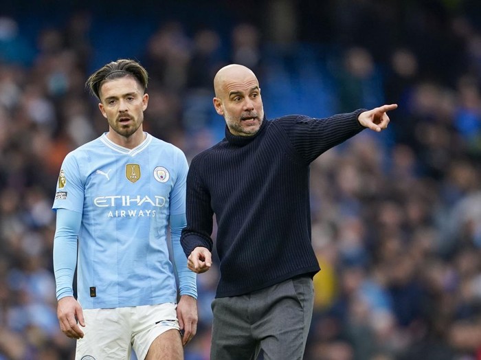 Manchester City's head coach Pep Guardiola, right, speaks with Manchester City's Jack Grealish at the end of the English Premier League soccer match between Manchester City and Arsenal at the Etihad stadium in Manchester, England, Sunday, March 31, 2024. (AP Photo/Dave Thompson)