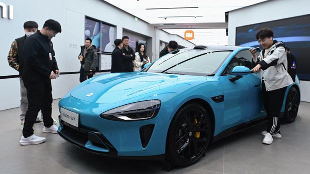 People look at a Xiaomi SU7 electric car displayed at a Xiaomi store in Beijing on March 26, 2024. (Photo by WANG Zhao / AFP)