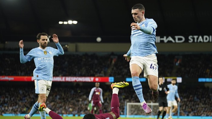 Aston Villas Diego Carlos, center, falls on the ground as Manchester Citys Phil Foden jumps over him during the English Premier League soccer match between Manchester City and Aston Villa at the Etihad Stadium in Manchester, England, Wednesday, April 3, 2024. (AP Photo/Dave Thompson)