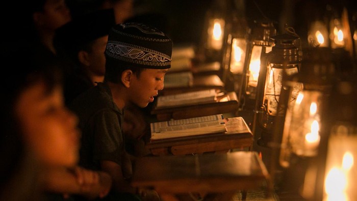 Seorang pembimbing mengajarkan seorang anak mengaji dengan penerangan lampu lilin dikala pengajian Tadarus Al Alquran di kampung Prajurit Wirotamtomo, Baluwarti, Solo, Jawa Tengah, Rabu (3/4/2024). Pengajian dalam rangka menyambut malam Lailatul Qadar tersebut untuk mendekatkan bawah umur dengan alam serta mendidik untuk tekun membaca Al Alquran utamanya pada bulan Ramadhan. ANTARA FOTO/Mohammad Ayudha/Spt.