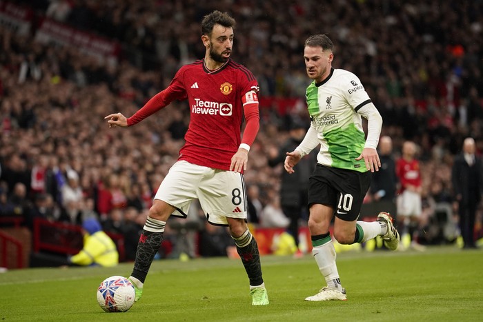 Manchester United's Bruno Fernandes, left, is challenged by Liverpool's Alexis Mac Allister during the FA Cup quarterfinal soccer match between Manchester United and Liverpool at the Old Trafford stadium in Manchester, England, Sunday, March 17, 2024. (AP Photo/Dave Thompson)