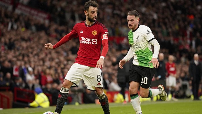 Manchester Uniteds Bruno Fernandes, left, is challenged by Liverpools Alexis Mac Allister during the FA Cup quarterfinal soccer match between Manchester United and Liverpool at the Old Trafford stadium in Manchester, England, Sunday, March 17, 2024. (AP Photo/Dave Thompson)