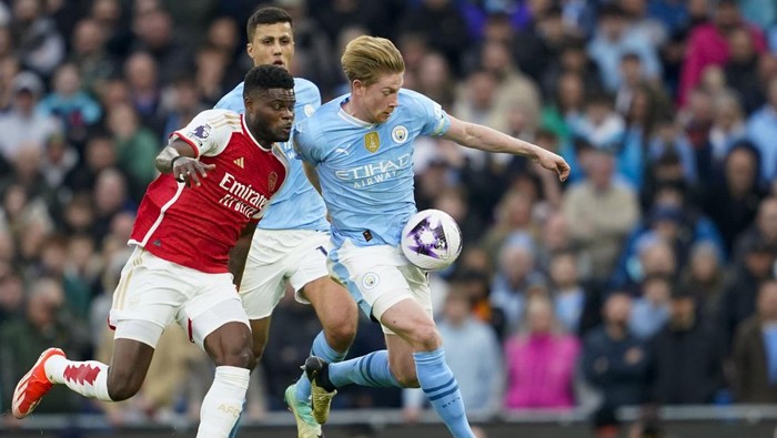 Arsenals Thomas Partey, left, duels for the ball with Manchester Citys Kevin De Bruyne during the English Premier League soccer match between Manchester City and Arsenal at the Etihad stadium in Manchester, England, Sunday, March 31, 2024. (AP Photo/Dave Thompson)