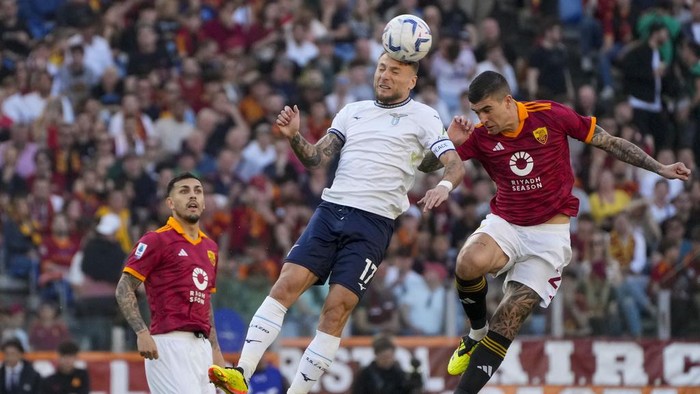 Lazios Ciro Immobile, center, jumps for the ball with Romas Gianluca Mancini during a Serie A soccer match between Roma and Lazio, at Stadio Olimpico, in Rome, Italy, Saturday, April 6, 2024. (AP Photo/Gregorio Borgia)