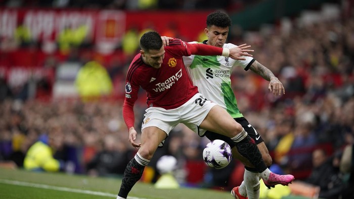 Manchester Uniteds Diogo Dalot, left, and Liverpools Luis Diaz challenge for the ball during the English Premier League soccer match between Manchester United and Liverpool at the Old Trafford stadium in Manchester, England, Sunday, April 7, 2024. (AP Photo/Dave Thompson)