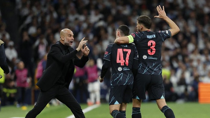 Soccer Football - Champions League - Quarter Final - First Leg - Real Madrid v Manchester City - Santiago Bernabeu, Madrid, Spain - April 9, 2024 Manchester Citys Phil Foden celebrates scoring their second goal with manager Pep Guardiola and Ruben Dias REUTERS/Juan Medina