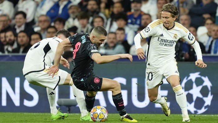 Manchester Citys Mateo Kovacic, center, fights for the ball with Real Madrids Luka Modric, right, during the Champions League quarterfinal first leg soccer match between Real Madrid and Manchester City at the Santiago Bernabeu stadium in Madrid, Spain, Tuesday, April 9, 2024. (AP Photo/Jose Breton)