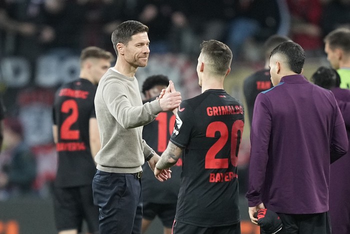 Leverkusen's head coach Xabi Alonso, centre left, celebrates with Leverkusen's Alex Grimaldo after the Europa League quarterfinals first leg soccer match between Bayer 04 Leverkusen and West Ham United at the BayArena in Leverkusen, Germany, Thursday, April 11, 2024. (AP Photo/Martin Meissner)