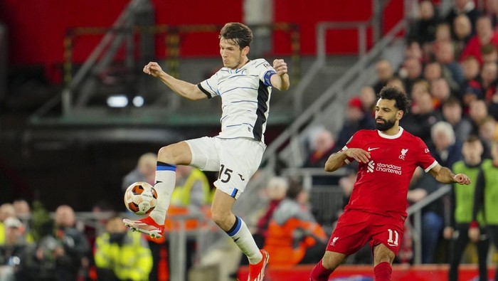 Atalantas Marten de Roon, center, controls the ball past Liverpools Mohamed Salah during the Europa League quarter final first leg soccer match between Liverpool and Atalanta, at the Anfield stadium in Liverpool, England, Thursday, April 11, 2024. (AP Photo/Jon Super)