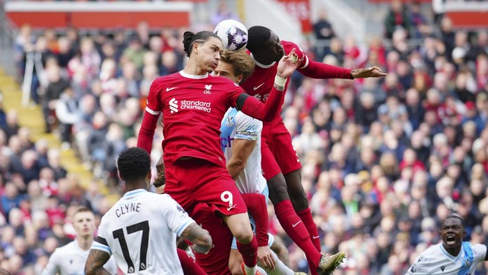 Liverpools Darwin Nunez, centre, challenges for the ball with Crystal Palaces Joachim Andersen during the English Premier League soccer match between Liverpool and Crystal Palace at Anfield Stadium in Liverpool, England, Sunday, April 14, 2024. (AP Photo/Jon Super)