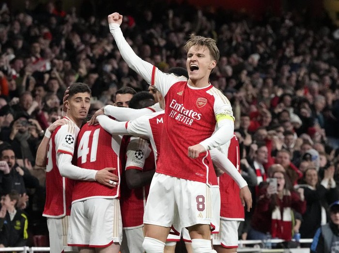 Arsenal's Martin Odegaard, center, celebrates after Bukayo Saka scored the opening goal during the Champions League quarter final first leg soccer match between Arsenal and Bayern Munich at the Emirates Stadium, London, Tuesday, April 9, 2024. (AP Photo/Frank Augstein)