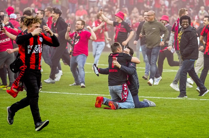 Leverkusen fans celebrate on the pitch after Bayer Leverkusen won the German Bundesliga title beating Werder Bremen in Leverkusen, Germany, Sunday, April 14, 2024. (AP Photo/Martin Meissner)