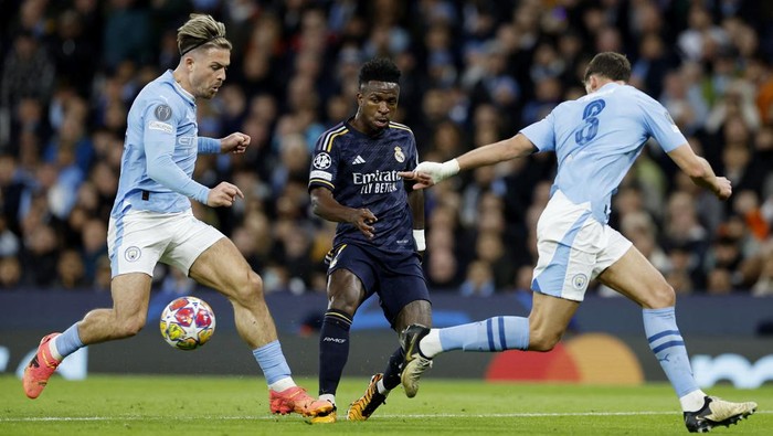 Kalahkan Juara Bertahan Man City, Real Madrid ke Semifinal Liga Champions Soccer Football - Champions League - Quarter Final - Second Leg - Manchester City v Real Madrid - Etihad Stadium, Manchester, Britain - April 17, 2024 Real Madrid's Vinicius Junior in action with Manchester City's Jack Grealish and Ruben Dias Action Images via Reuters/Jason Cairnduff